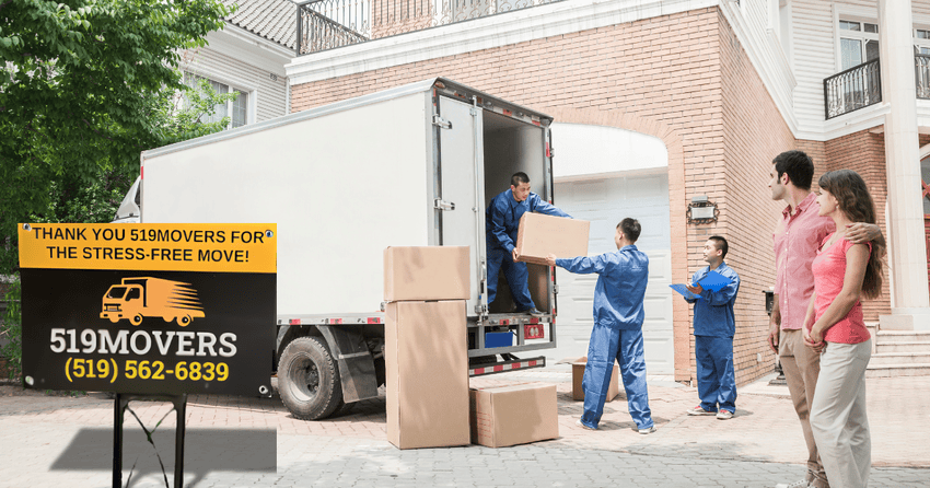 Professional movers loading boxes in truck and helping a couple relocate.