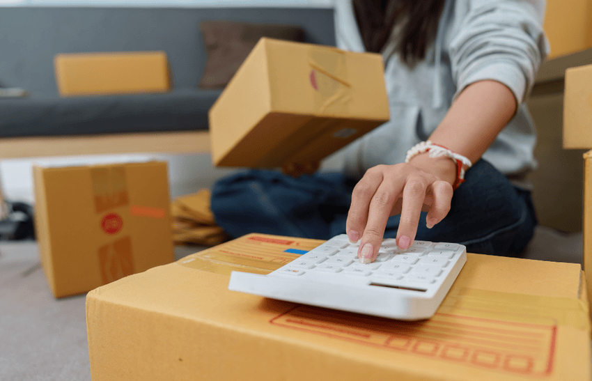 A woman holding a box and calculating how much do movers cost in London Ontario.