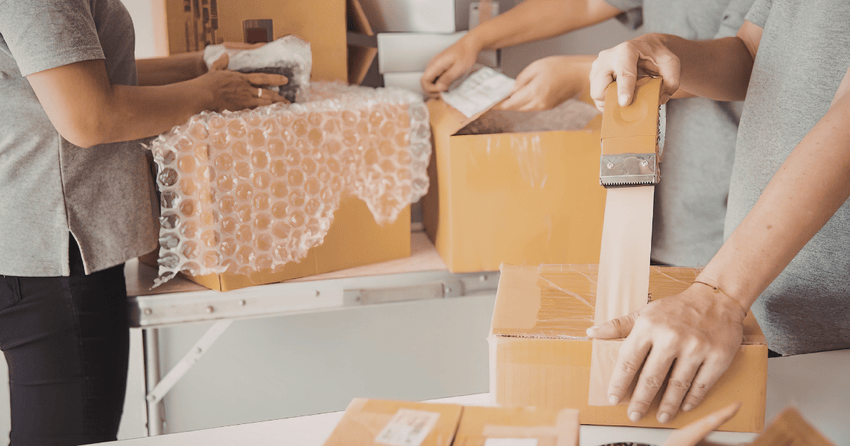 Three movers using essential packing supplies to carefully pack all items. 