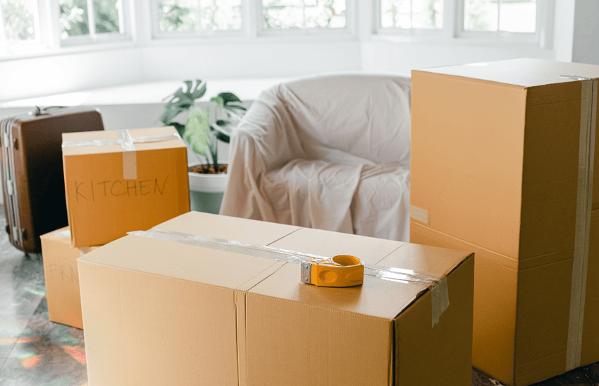 Several packed boxes are placed in living room showing how to prepare your home before professional movers arrive.