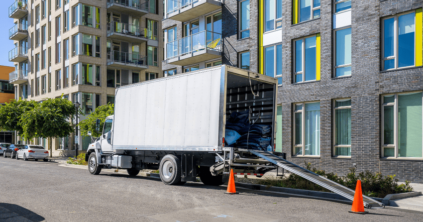 A moving truck is parked infront of apartment complex. 